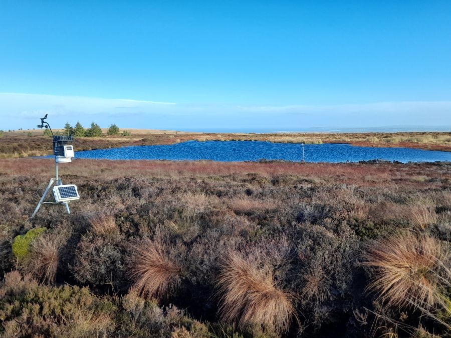 Altikeeragh Bog with a large area of open water and monitoring equipment set up amongst heather