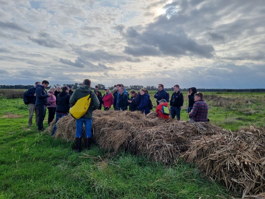 Group on a site visit, sat on, or standing around a harvested crop.