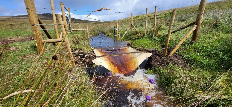 Brown peaty water flowing through a flume on Divis Mountain