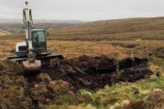Machine operator reprofiling a peat hag at Dryhope Farm. 