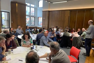 Researchers, practitioners and policy-makers from across Europe sitting in groups of 8 to 10 people at three tables discussing ways to standardise the collection of environmental data to better understand how peatlands respond to climate change, land use and restoration to inform policy and practice.
