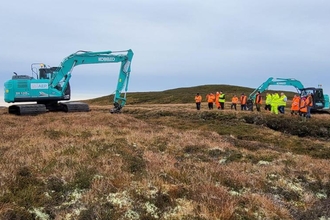 A group of machine operators new to peatland restoration watching an experienced machine operator reprofiling an eroding gully.