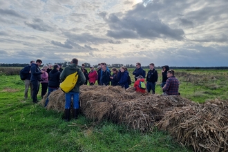 Group of people sat on or around bales in a field