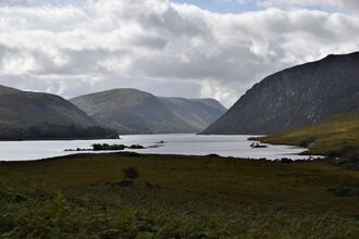 Peatland landscape at Glenveagh National Park with a lough and mountains in the background