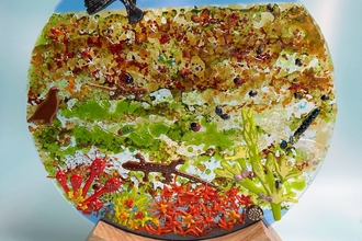 Flat glass sculpture depicting a peatland scene, with a hen harrier, red grouse, dragonfly, lizard, sundews and Sphagnum moss
