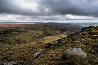 Moorland landscape looking across a valley with a brooding grey sky above.