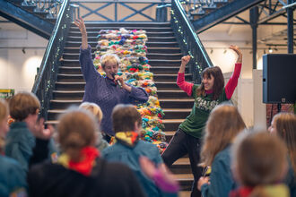 Two young people with their arms in the air in front of a group of children.