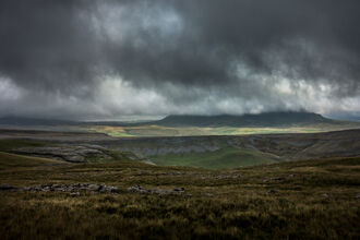 Moorland landscape with low, brooding clouds hiding a distant peak.