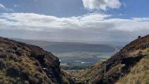 Landscape image with hills on either side of the picture and a valley running through the middle