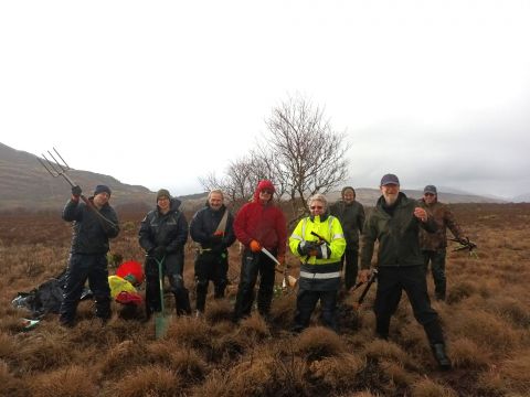 Group of people on a bog restoration work party. They are holding tools and wearing outdoor clothing.