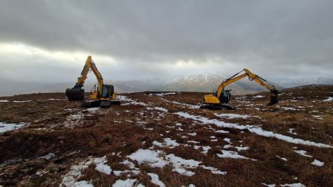 Two diggers carrying out work on a snowy peatland