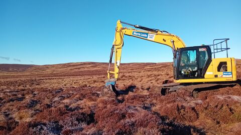 Yellow digger digging on brown peatland