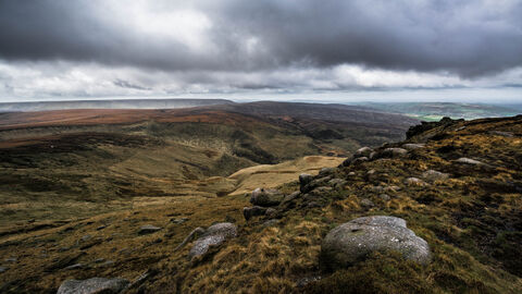 Moorland landscape looking across a valley with a brooding grey sky above.