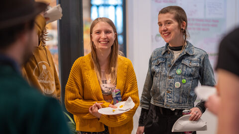 Two young people smiling and holding paper plates.