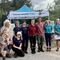 A group of people stood in a line, smiling at the camera. Behind them is a marquee with 'Dorset Wildlife Trust' written on it, alongside their badger logo.