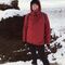 Person in warm outdoor clothing stood in a snowy landscape.