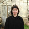 Person in black looking at the camera with a large greenhouse in the background.