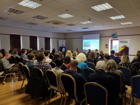 A group of people sitting in a rooms looking at a presentation