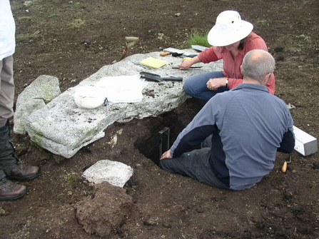 Two people recovering samples of peat from under one of the Cut Hill stones.