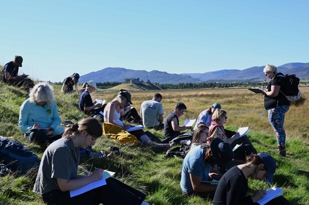 People writing in the sunshine at a workshop held outside