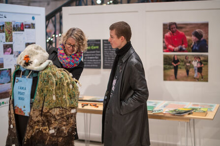 A young person looking at an artist's dummy displaying a woollen poncho.