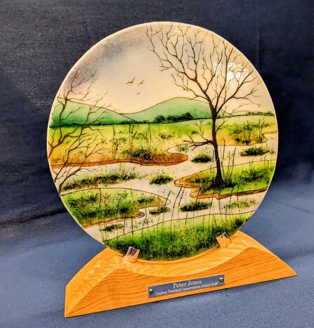 Round glass plate with a peatland scene in a wooden holder.