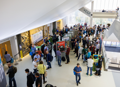 A group of conference delegates browsing posters in an exhibition space.